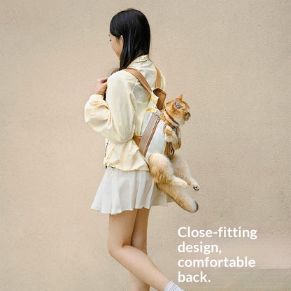 Woman wearing a beige jacket with a cat in a backpack against a beige background