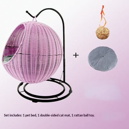 Pink wicker pet bed with stand, double-sided cat mat, and rattan ball toy on a gradient background.