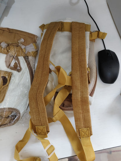 A close-up of a beige and tan backpack shown from the back, featuring adjustable tan webbing straps, mesh side panels, and plastic buckle closures, placed on a white desk next to a black computer mouse.