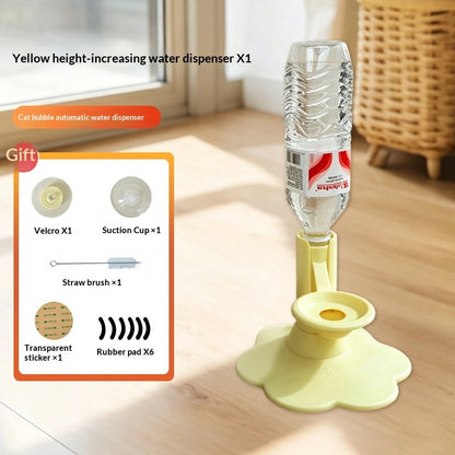 Yellow height-increasing water dispenser with a clear plastic bottle inverted in it, shown on a wooden floor in a home setting. An inset graphic on the left lists included accessories: Velcro, suction cup, straw brush, transparent sticker, and rubber pads.