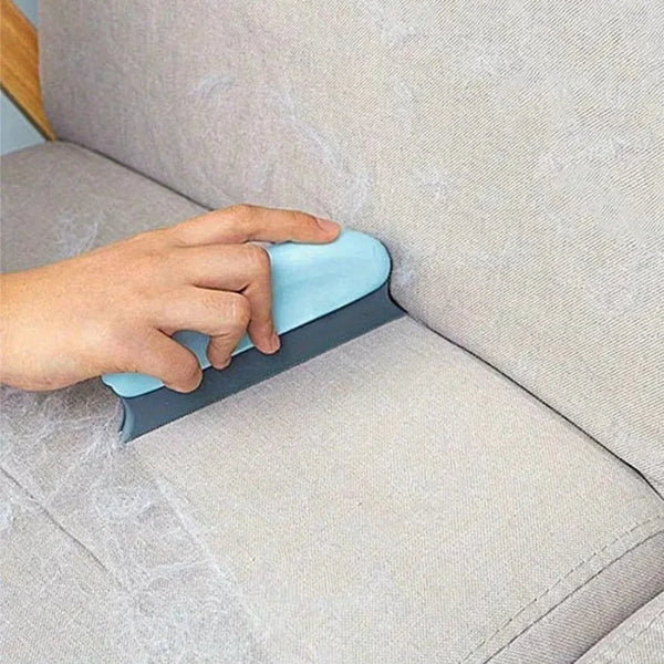 Hand using a blue and gray tool on a beige sofa