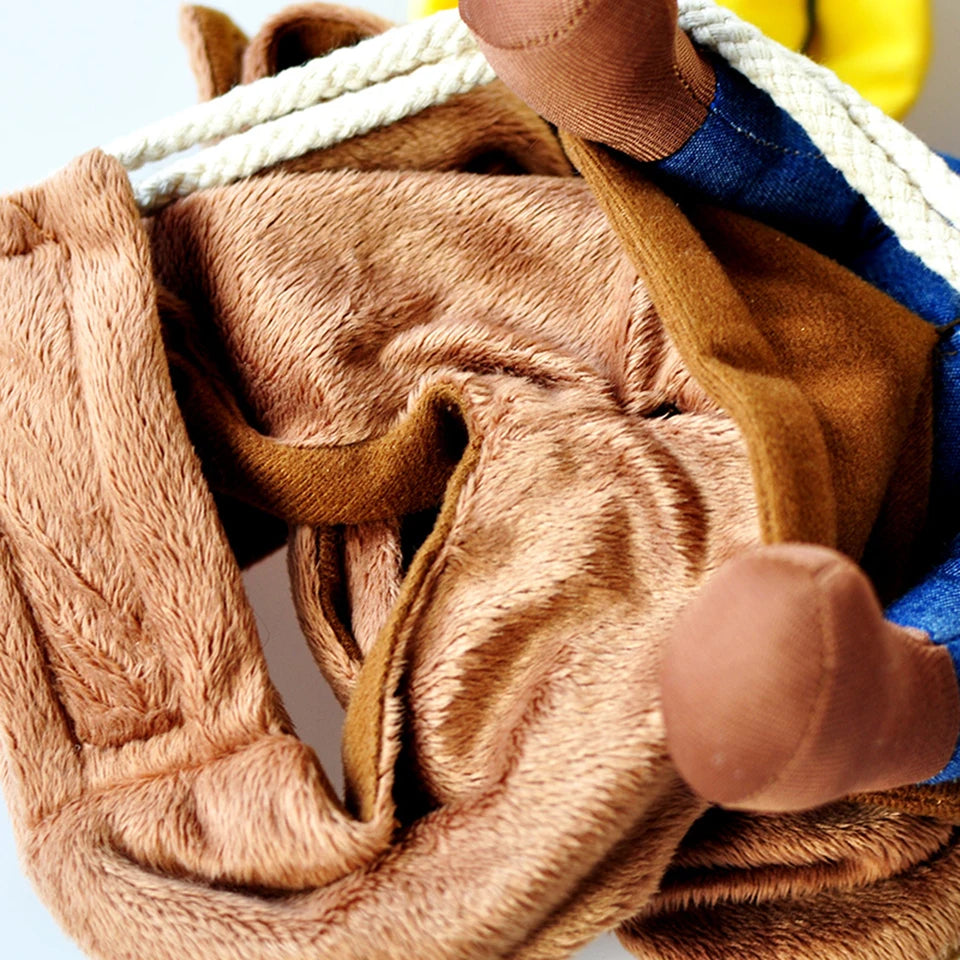 Close-up of a brown teddy bear with a blue shirt and yellow pants, wrapped in a beige blanket.