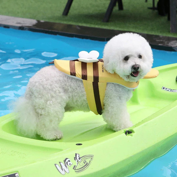Small white dog in a yellow life jacket on a green kayak in a pool.