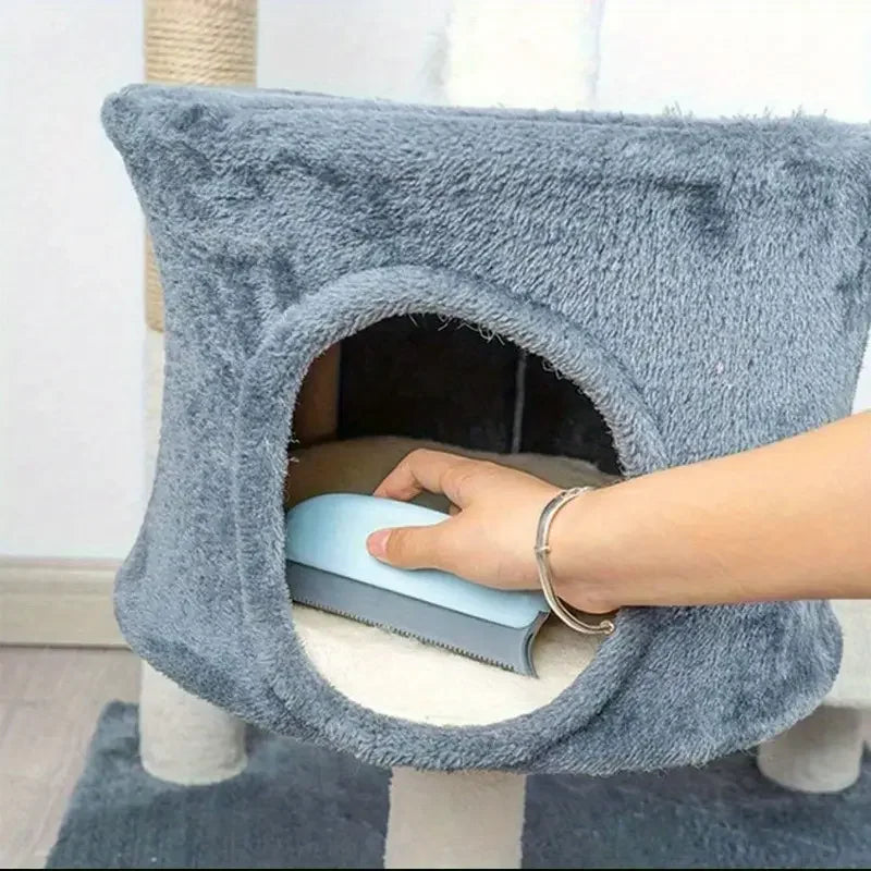 Person using a blue tool inside a gray cat bed attached to a scratching post.