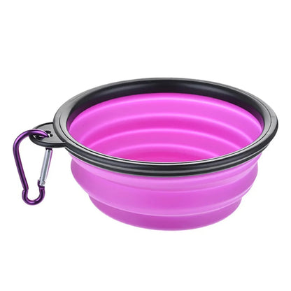 Pink collapsible dog bowl with black rim and purple carabiner on a white background