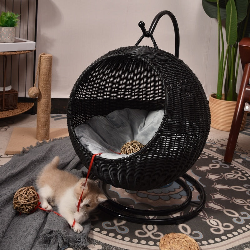 Black wicker pet bed with a puppy playing nearby on a patterned rug.